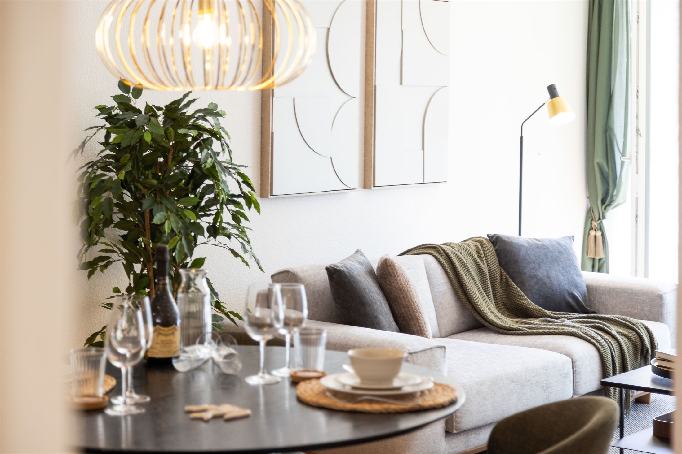 Wohnraum in St. Gallen mit hellem Sofa, grüner Wolldecke, Esstisch und Pflanze